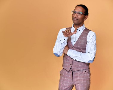 Kısa saçlı, beyaz dişli, pembe arka planda iş elbisesi giymiş genç bir Afro-Amerikan 'ın portresi. Kameranın önünde dikilip konuşmak..