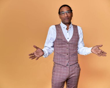 Kısa saçlı, beyaz dişli, pembe arka planda iş elbisesi giymiş genç bir Afro-Amerikan 'ın portresi. Kameranın önünde dikilip konuşmak..