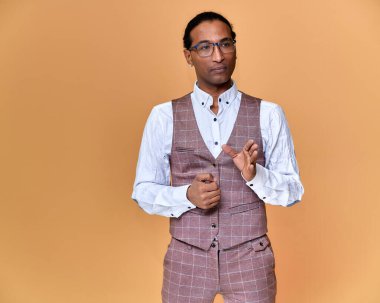 Kısa saçlı, beyaz dişli, pembe arka planda iş elbisesi giymiş genç bir Afro-Amerikan 'ın portresi. Kameranın önünde dikilip konuşmak..