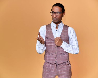 Kısa saçlı, beyaz dişli, pembe arka planda iş elbisesi giymiş genç bir Afro-Amerikan 'ın portresi. Kameranın önünde dikilip konuşmak..