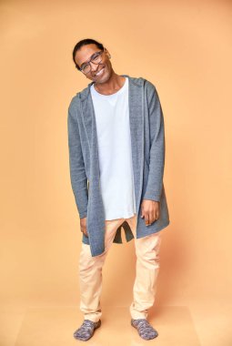 Gözlüklü, Afro-Amerikan kısa saçlı, pembe arka planda kısa saçlı neşeli bir gencin dikey portresi. Kameranın önünde dikiliyorum.