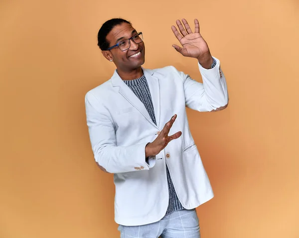 Portrait of a young African American man with short haircuts and a white-toothed smile in a white jacket on a pink background. Standing and talking right in front of the camera. — Stock Photo, Image
