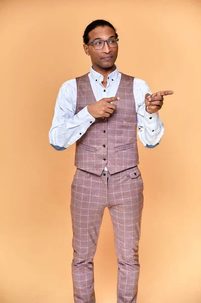 Vertikalt porträtt Ung man med kort hår afroamerikan i en kostym på en rosa bakgrund. Stå och prata framför kameran. — Stockfoto