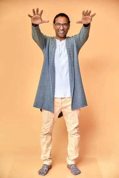 Vertical portrait of a cheerful young man wearing glasses African-American with a short haircut in ordinary clothes on a pink background in full length. Standing right in front of the camera — Stock Photo, Image
