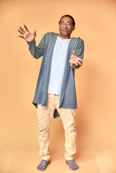 Retrato vertical de un joven alegre con gafas afroamericanas con un corte de pelo corto en ropa ordinaria sobre un fondo rosa en toda su longitud. De pie justo delante de la cámara —  Fotos de Stock