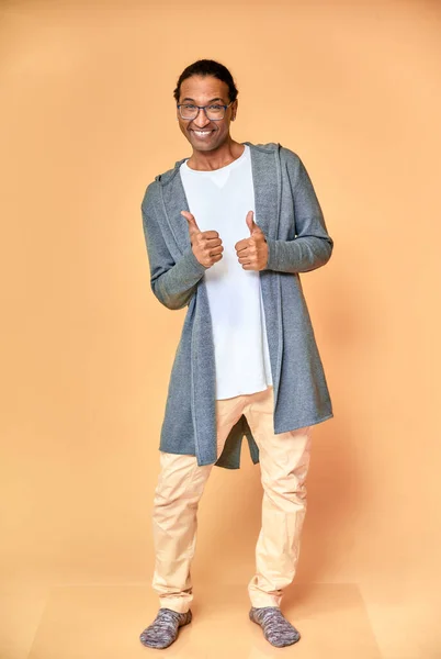 Вертикальный портрет веселого молодого человека в очках афроамериканца с короткой стрижкой в обычной одежде на розовом фоне в полный рост. Стоя прямо перед камерой — стоковое фото