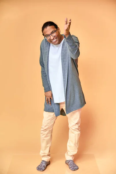 Retrato vertical de un joven alegre con gafas afroamericanas con un corte de pelo corto en ropa ordinaria sobre un fondo rosa en toda su longitud. De pie justo delante de la cámara —  Fotos de Stock