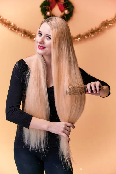 Porträtt av en söt tjej i svart T-shirt med långt vackert hår och fantastisk makeup. Begreppet ung blond kvinna med nyårsinredning. Leende, visar känslor på en rosa bakgrund. — Stockfoto