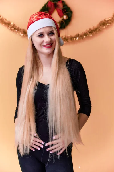 Retrato de una linda chica en una camiseta negra con pelo largo y hermoso y gran maquillaje. Concepto de una joven rubia con decoración de Año Nuevo. Sonriendo, mostrando emociones sobre un fondo rosado . —  Fotos de Stock