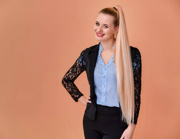 Concepto de negocio chica rubia se para delante de la cámara. Retrato de una mujer gerente en un traje de negocios con pelo largo y hermoso y excelente maquillaje sobre un fondo rosa . — Foto de Stock