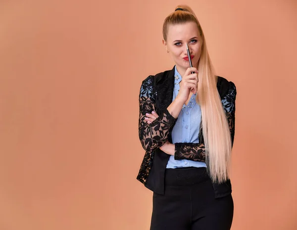 Conceito menina loira de negócios fica na frente da câmera. Retrato de uma mulher gerente em um terno de negócios com cabelo longo e bonito e excelente maquiagem em um fundo rosa . — Fotografia de Stock