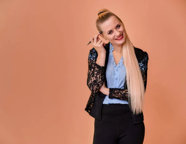 Concepto de negocio chica rubia se para delante de la cámara. Retrato de una mujer gerente en un traje de negocios con pelo largo y hermoso y excelente maquillaje sobre un fondo rosa . — Foto de Stock