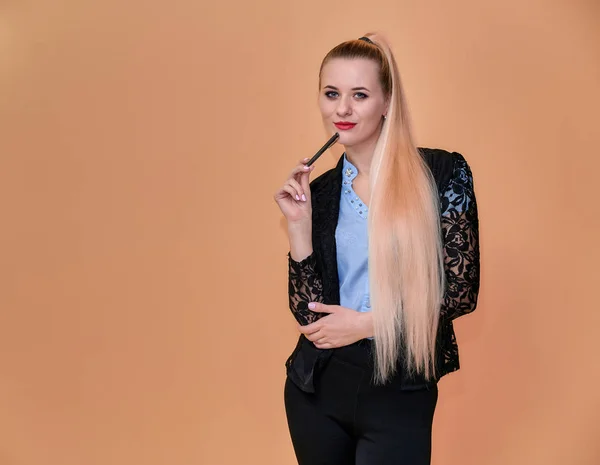 Konzept Business Blondes Mädchen steht vor der Kamera. Porträt einer Managerin im Business-Anzug mit langen, schönen Haaren und exzellentem Make-up auf rosa Hintergrund. — Stockfoto