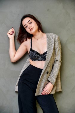 Alternatif bir iç mekanda gri arka planda gri ceketli, esmer, beyaz bir kızın portresi. Farklı pozlarda kameranın önünde durmak..