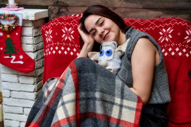 Evinde, yılbaşında gri kazaklı, esmer, beyaz bir kızın portresi. Kameranın önünde çeşitli pozlarda ekoseyle oturuyor..