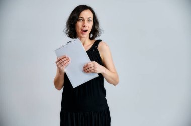 Siyah elbiseli güzel esmer bir kadının portresi. Beyaz bir arka planda dosyası var. Duygularını ellerinin farklı pozlarda kameranın önünde gösteriyor..