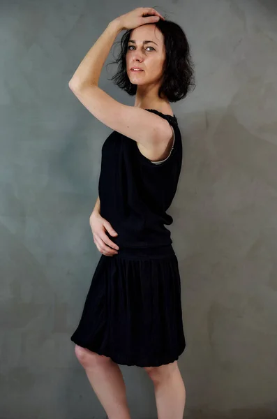Full length portrait of a pretty emotional brunette woman in black dress on alternative gray background in vintage interior. Standing right in front of the camera. — 스톡 사진