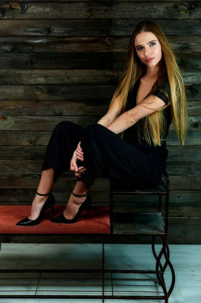 The model sits in various poses in front of the camera on a stand. The concept of fashion and style. Portrait of a pretty blonde girl with long hair and great makeup on a wooden background. — Stok fotoğraf