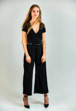 Model student manager stands in different poses in front of the camera in the studio. Full-length portrait of a pretty blonde girl with long hair and excellent make-up on a white background.