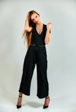 The concept of fashion and style. The model stands in different poses in front of the camera. Full-length portrait of a pretty blonde girl with long hair and excellent make-up on a white background.