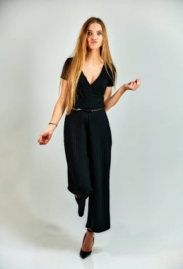 The model stands in different poses in front of the camera. The concept of fashion and style. Full-length portrait of a pretty blonde girl with long hair and excellent make-up on a white background.