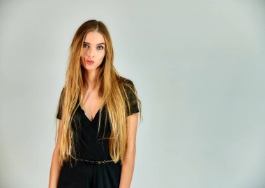 The concept of fashion and style. Portrait of a pretty blonde girl with long hair and great makeup on a white background. The model stands in different poses in front of the camera.