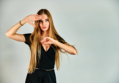 The model stands in different poses in front of the camera. The concept of fashion and style. Portrait of a pretty blonde girl with long hair and great makeup on a white background.
