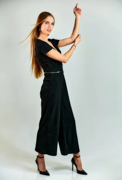 Full-length portrait of a pretty blonde girl with long hair and excellent make-up on a white background. Model student manager stands in different poses in front of the camera in the studio. — Stockfoto