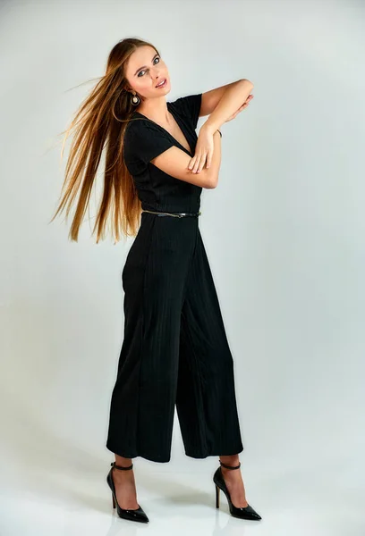 Full-length portrait of a pretty blonde girl with long hair and excellent make-up on a white background. Model student manager stands in different poses in front of the camera in the studio. — ストック写真