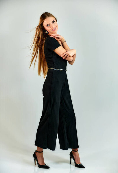 Full-length portrait of a pretty blonde girl with long hair and excellent make-up on a white background. Model student manager stands in different poses in front of the camera in the studio.