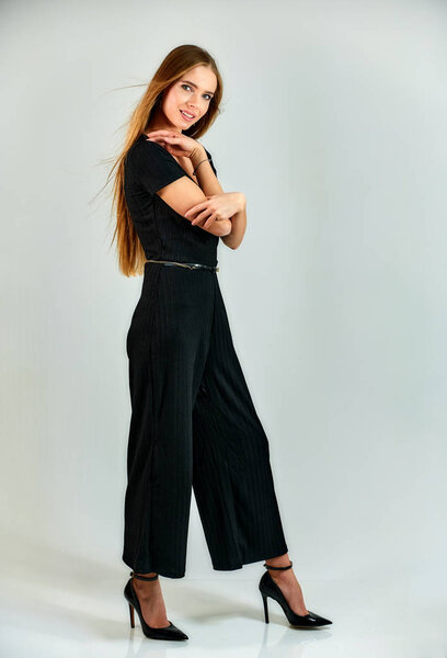 Full-length portrait of a pretty blonde girl with long hair and excellent make-up on a white background. Model student manager stands in different poses in front of the camera in the studio.