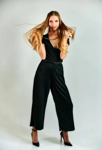 Full-length portrait of a pretty blonde girl with long hair and excellent make-up on a white background. Model student manager stands in different poses in front of the camera in the studio. — Stock fotografie