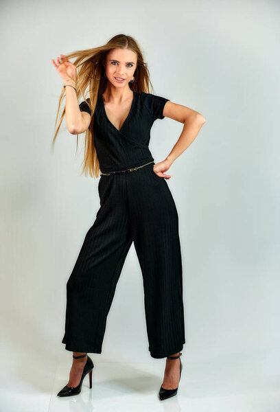 Model student manager stands in different poses in front of the camera in the studio. Full-length portrait of a pretty blonde girl with long hair and excellent make-up on a white background.