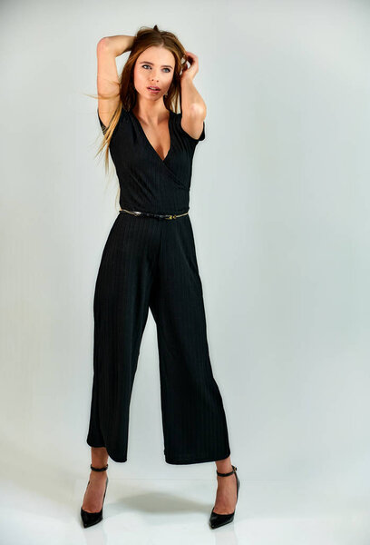 The concept of fashion and style. The model stands in different poses in front of the camera. Full-length portrait of a pretty blonde girl with long hair and excellent make-up on a white background.