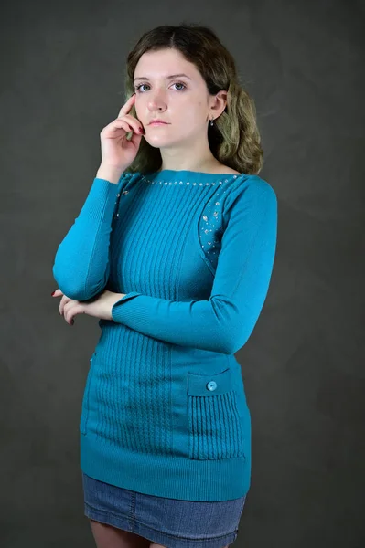Ritratto di una bella studentessa con bei capelli ricci è in piedi davanti alla fotocamera su uno sfondo grigio. Concetto foto verticale di una giovane donna con emozioni in un vestito blu . — Foto Stock