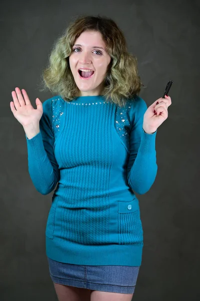 Αντίληψη κάθετη φωτογραφία μιας νεαρής γυναίκας με συναισθήματα σε ένα μπλε φόρεμα. Πορτρέτο ενός όμορφου μαθητή κορίτσι με όμορφα σγουρά μαλλιά στέκεται μπροστά από την κάμερα σε ένα γκρι φόντο. — Φωτογραφία Αρχείου