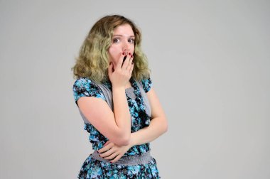 Turkuaz elbiseli genç bir kadının yatay fotoğrafı beyaz arka planda kameranın önünde duruyor. Güzel, muhteşem saçları olan bir kızın portresi..