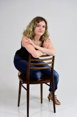 Genç bir kadın sandalyede oturuyor.