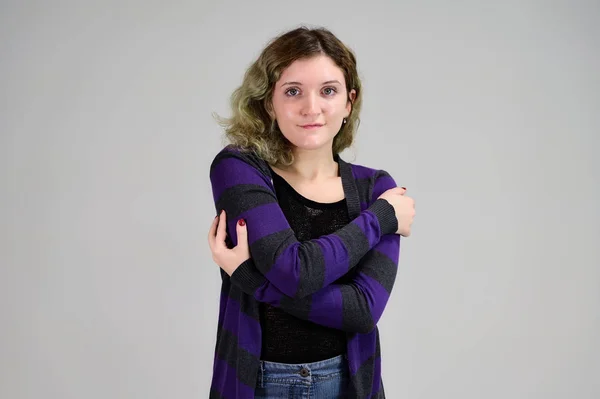 Porträtt av en söt elev med vackert lockigt hår. Begreppet horisontellt foto av en ung kvinna med känslor i en mörk jacka står framför kameran på en vit bakgrund. — Stockfoto