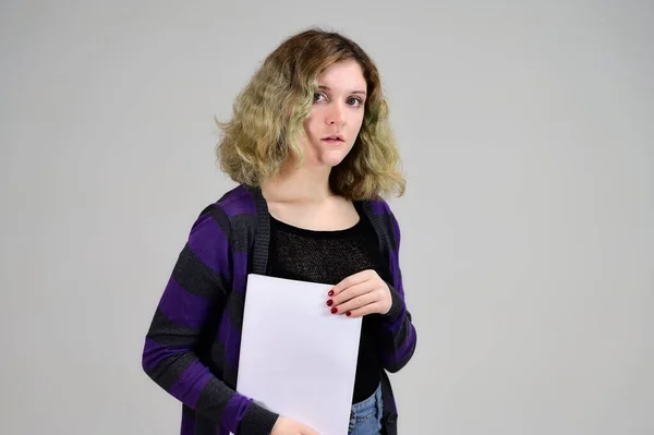 Concept horizontal photo of a young woman with emotions in a dark jacket standing in front of the camera on a white background. Portrait of a student girl with a folder in her hands with fluffy hair. — Stock Photo, Image