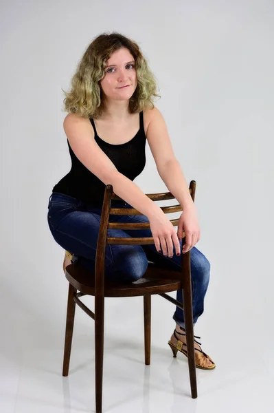 Μια νεαρή γυναίκα κάθεται σε μια καρέκλα — Φωτογραφία Αρχείου