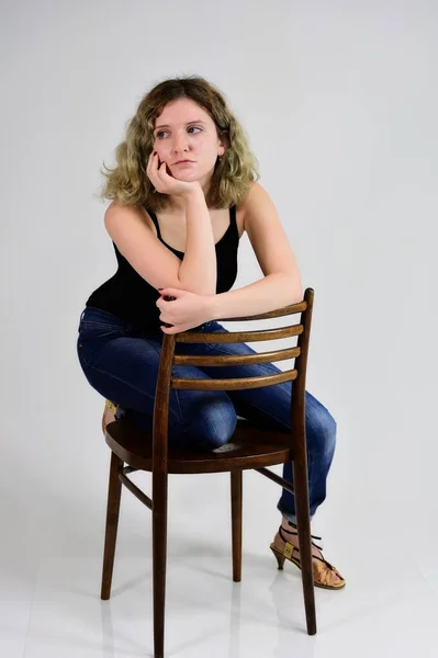 En ung kvinna sitter på en stol — Stockfoto