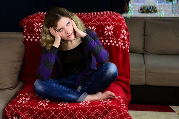 Koncepcyjne zdjęcie młodej kobiety w swetrze i dżinsach siedzącej na krześle przed kamerą we wnętrzu domu. Na kanapie brakuje portretu dziewczyny o pięknych, pięknych włosach. — Zdjęcie stockowe