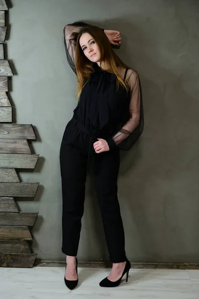 Full-length φωτογραφία ενός όμορφου μελαχρινού κοριτσιού με εξαιρετικό μακιγιάζ σε σκούρα ρούχα που στέκεται σε γκρι φόντο σε πολυτελές vintage εσωτερικό. Η έννοια της ένα λαμπερό πορτρέτο. — Φωτογραφία Αρχείου