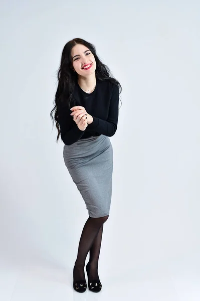 Konzept des Business weibliches Fotoporträt. ein brünettes Mädchen mit einem Lächeln mit langen Haaren und ausgezeichnetem Make-up in einem grauen Kleid auf weißem Hintergrund steht in verschiedenen Posen in vollem Wachstum. — Stockfoto