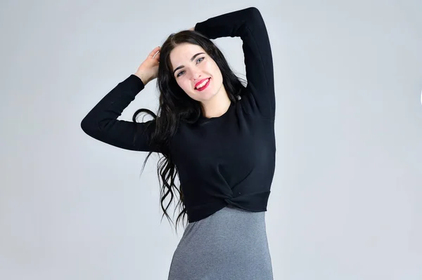 Concept of business female photo portrait with emotions. Portrait of a brunette girl with a smile with long hair with excellent makeup in a gray dress on a white background in different poses. — Stock Photo, Image