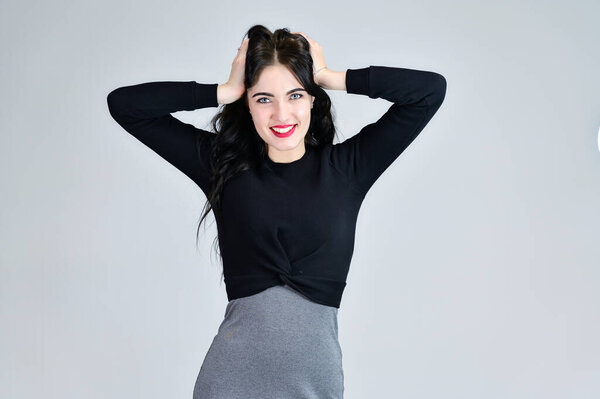 Concept of business female photo portrait with emotions. Portrait of a brunette girl with a smile with long hair with excellent makeup in a gray dress on a white background in different poses.