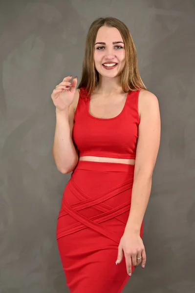 Вертикальне фото досить усміхненої дівчини з довгим волоссям і чудовим макіяжем у червоній сукні з емоціями в різних позах. Універсальна концепція жіночого портрета . — стокове фото