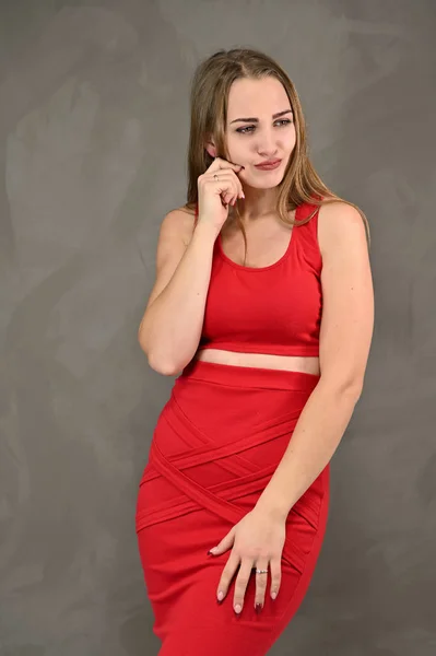 Παγκόσμια έννοια του γυναικείου πορτρέτου. Κάθετη φωτογραφία ενός όμορφου χαμογελαστού κοριτσιού με μακριά μαλλιά και υπέροχο μακιγιάζ σε κόκκινο φόρεμα με συναισθήματα σε διαφορετικές πόζες. — Φωτογραφία Αρχείου