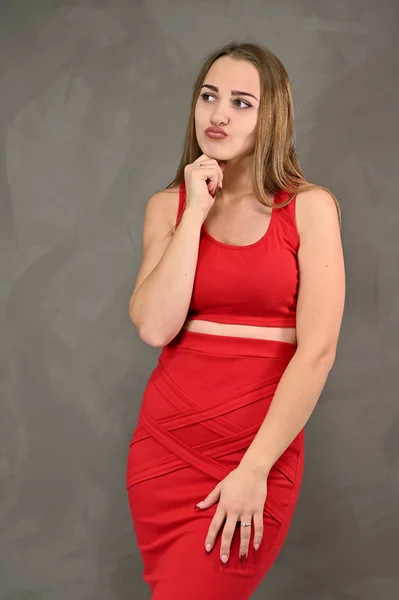 Concepto universal de retrato femenino. Foto vertical de una chica muy sonriente con el pelo largo y un gran maquillaje en un vestido rojo con emociones en diferentes poses . —  Fotos de Stock